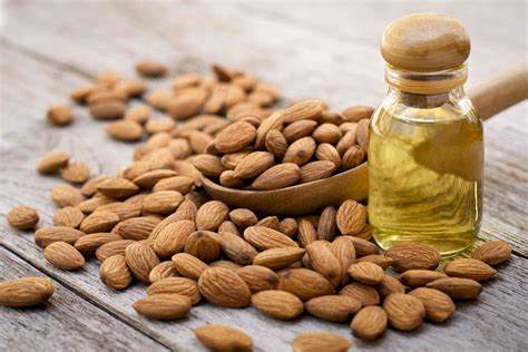 Almonds and a bottle of almond oil on a wooden surface